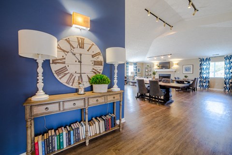 a living room with a large clock on the wall and a table with chairs