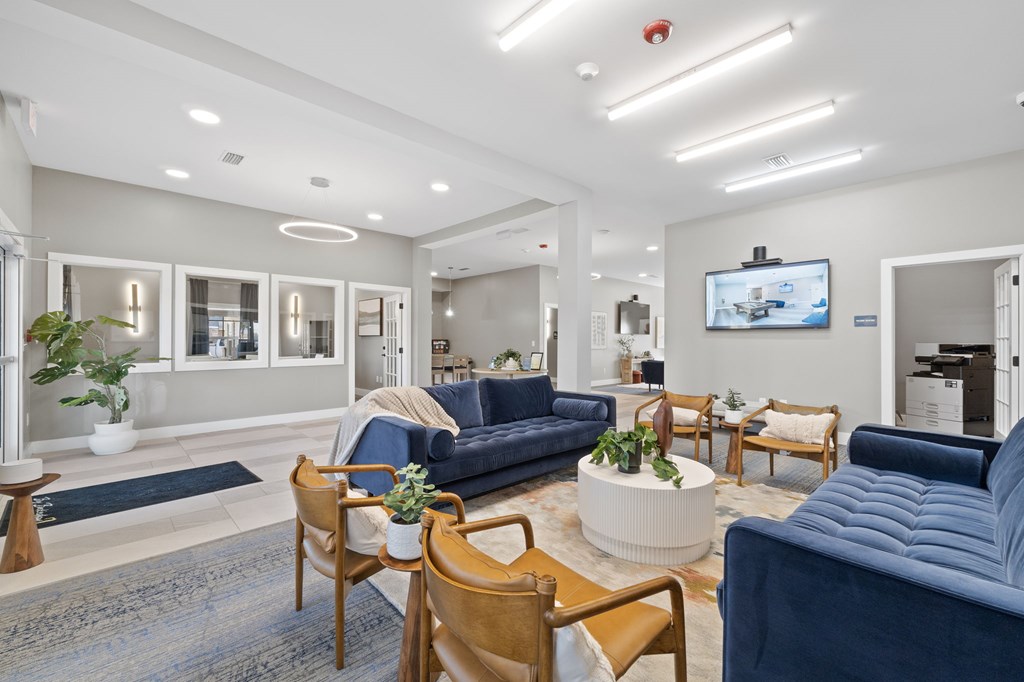A living room with a blue couch and wooden chairs.
