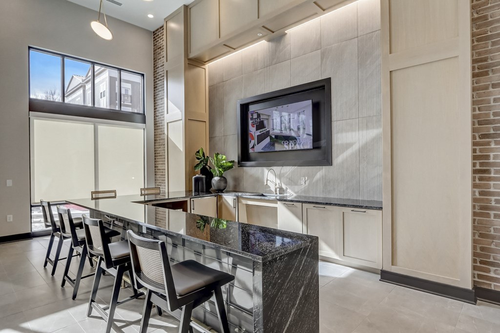a kitchen with a bar with chairs and a tv on the wall