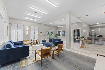A spacious living room with blue sofas and wooden chairs.