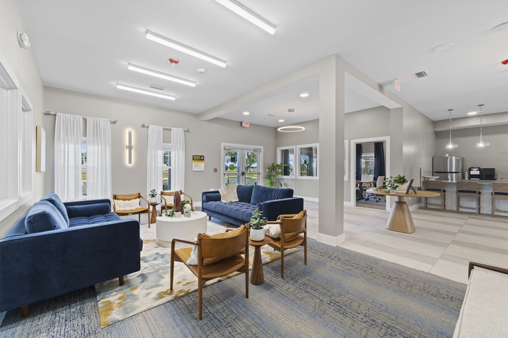 A spacious living room with blue sofas and wooden chairs.