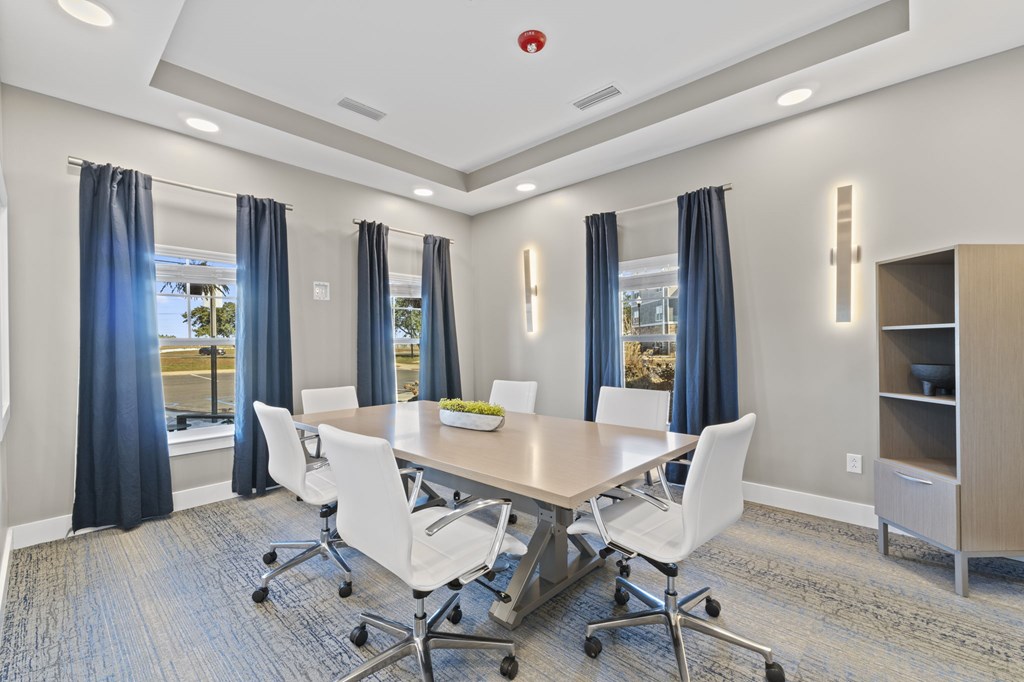 A conference room with a table, chairs, and a window with curtains.