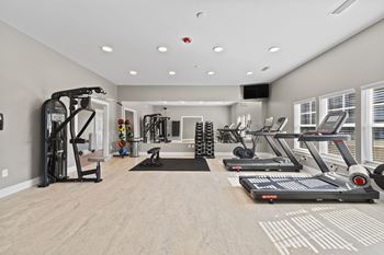 Fully equipped gym at The Rivi Apartments in Foley, AL, with treadmills, strength training equipment, and free weights.