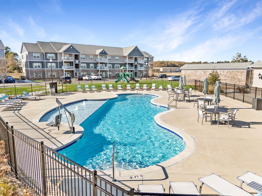 A large swimming pool with a slide and a building in the background.
