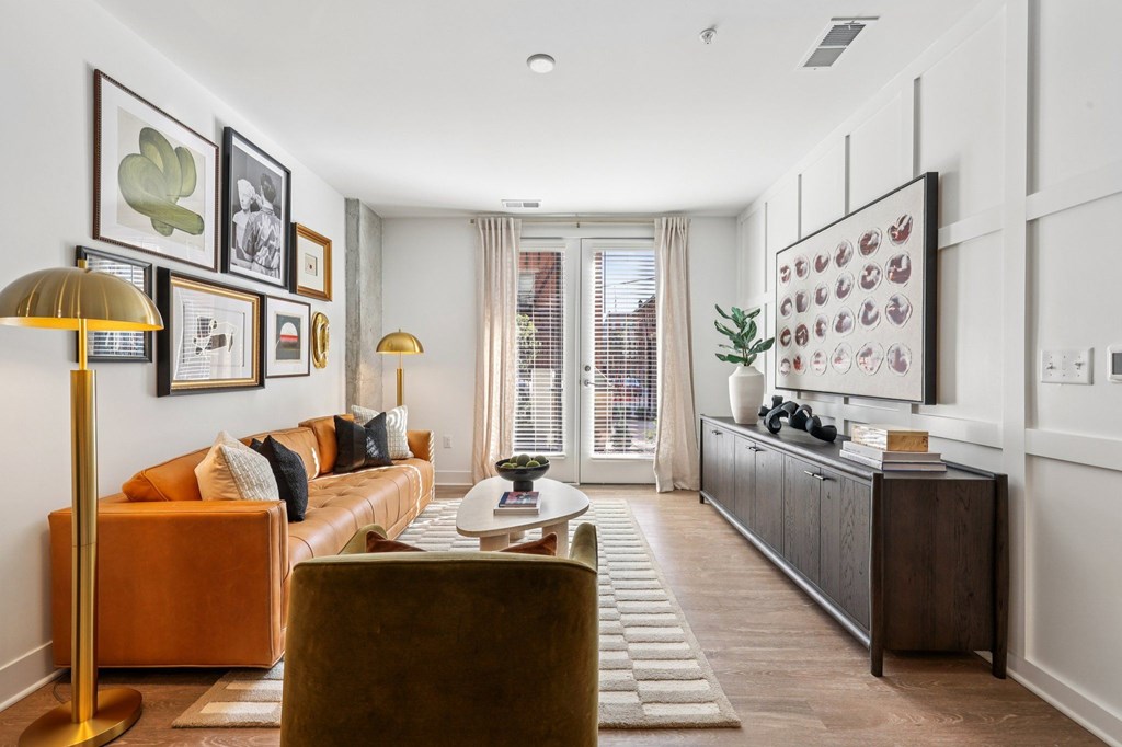 Stylish living area at Contrast OTR in Over-the-Rhine, Cincinnati featuring leather sofa, curated artwork, and natural light from French doors.