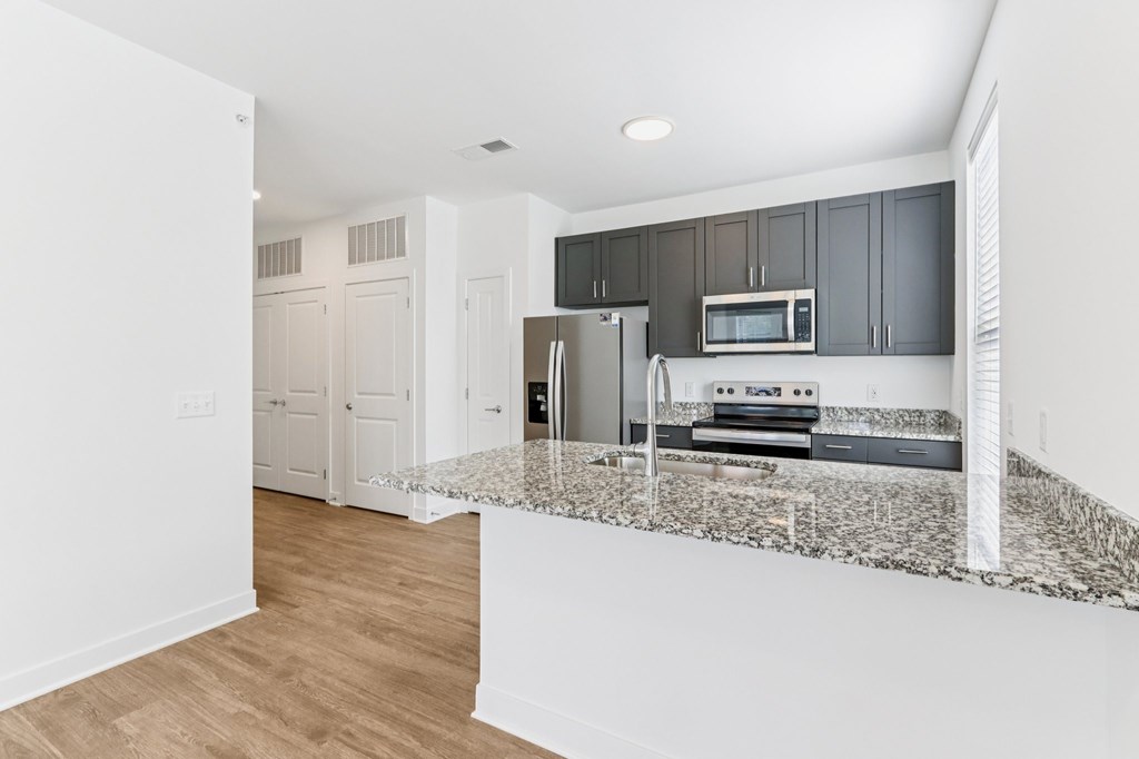 Open kitchen layout with dark cabinets and island at Nook Nine Apartments
