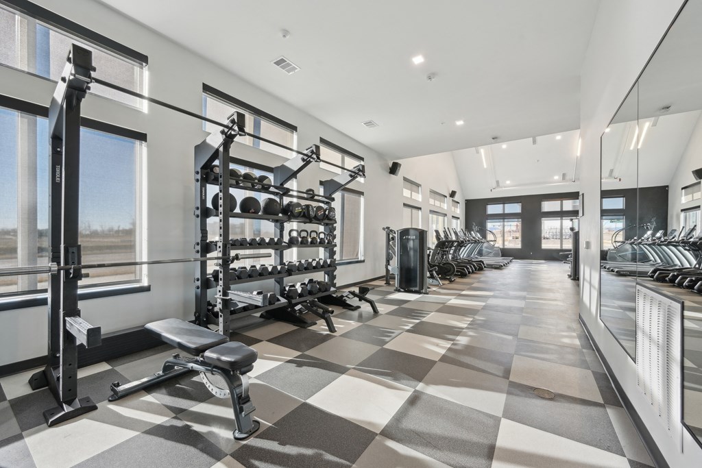 A spacious gym with a variety of equipment and a checkered floor.