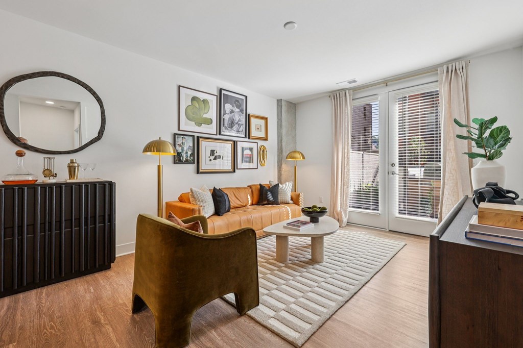 Modern living room at Contrast OTR apartments in Cincinnati, OH with tan leather sofa, gallery wall decor, and warm lighting.