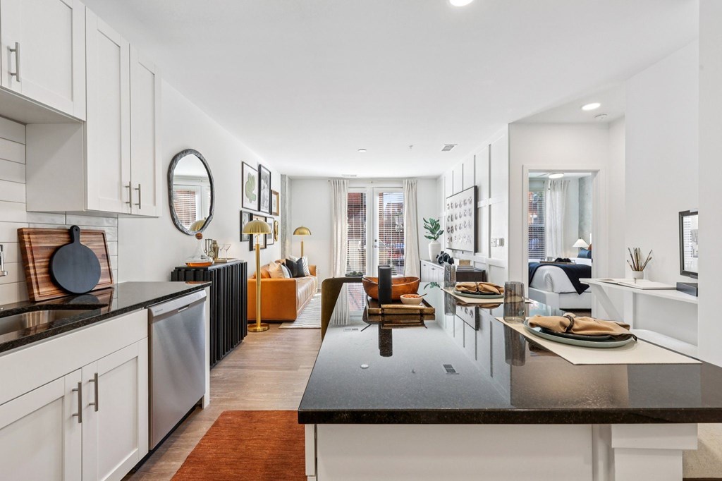 A modern kitchen with a black countertop and white cabinets.