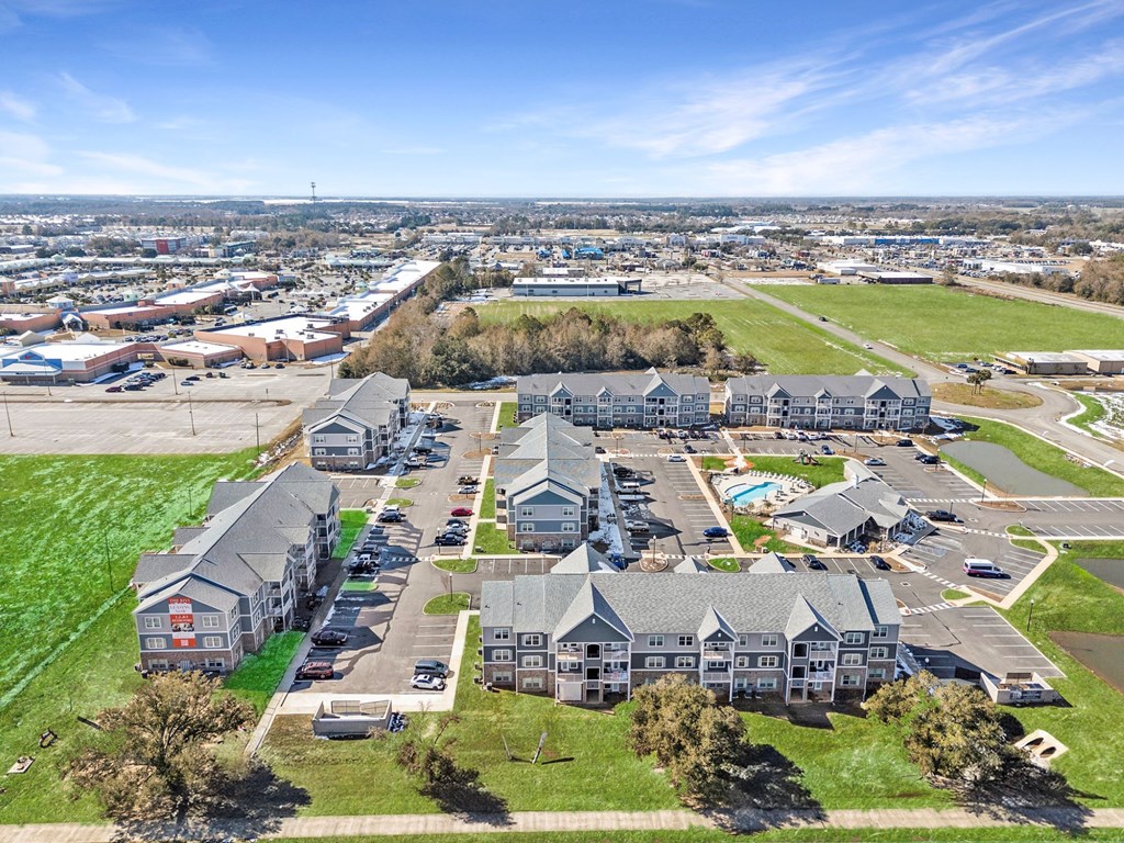 A large, modern building complex with a parking lot in front.