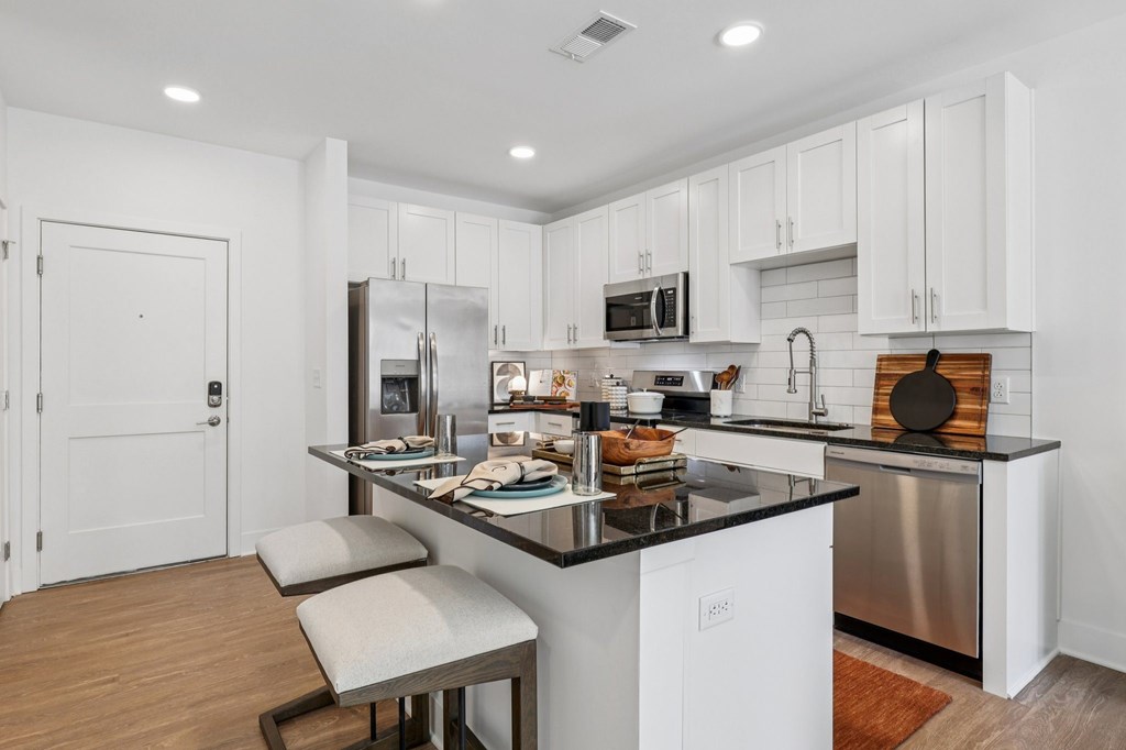 A modern kitchen with white cabinets and a black countertop.