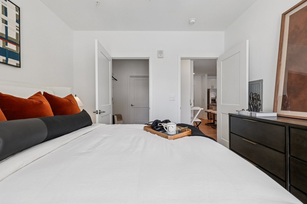 Bright bedroom at Contrast OTR in Cincinnati, OH with green accent decor, modern artwork, and soft lighting.