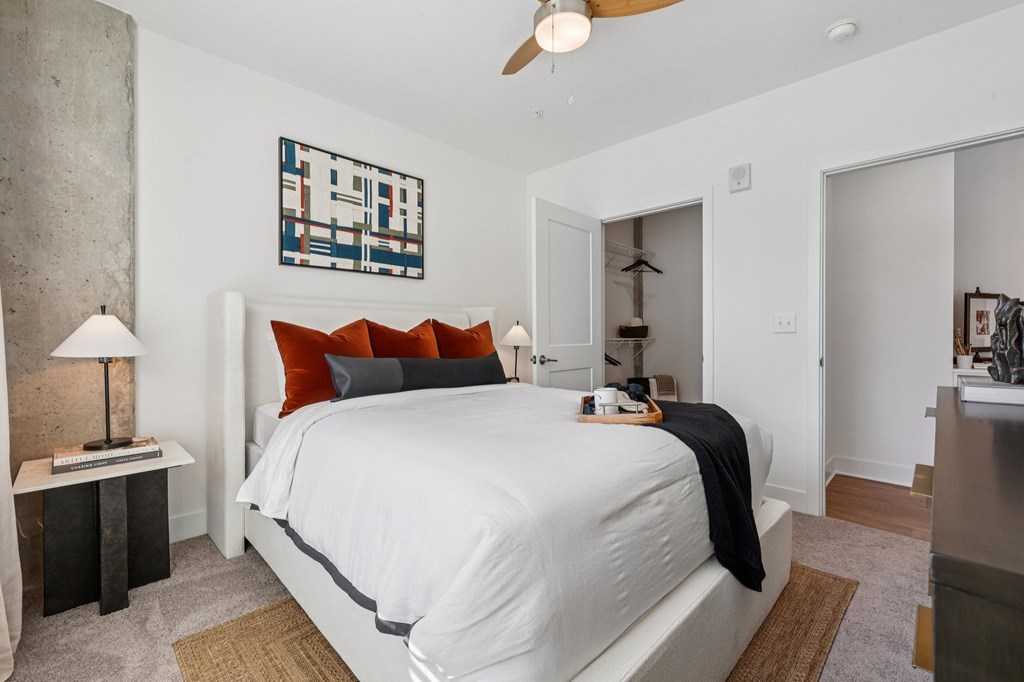 Bedroom at Contrast OTR in Cincinnati, OH with mid-century modern decor, wood nightstand, and bright window views.