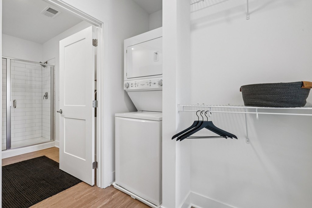 In-home laundry at Contrast OTR in Cincinnati, OH with stacked washer and dryer near walk-in closet and modern bathroom.