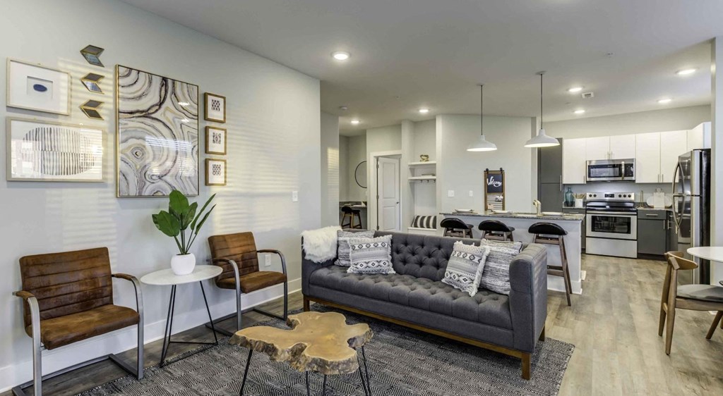 a living room with a couch and a kitchen in the background at Echo Park at Perry Crossing Apartments, Indiana, 46168