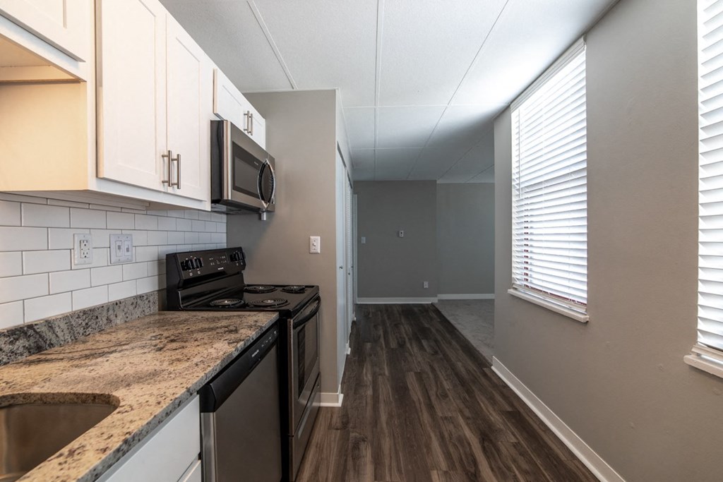 Brightly lit kitchen with granite countertops and hardwood floors at