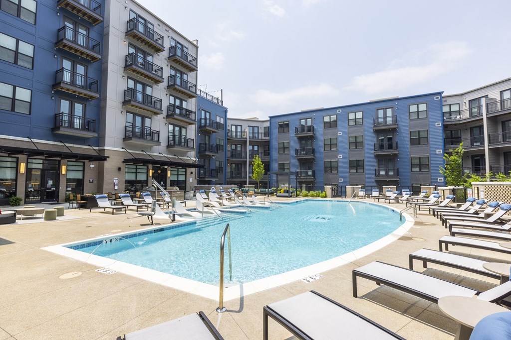 a large swimming pool with chaise lounge chairs and a building in the background