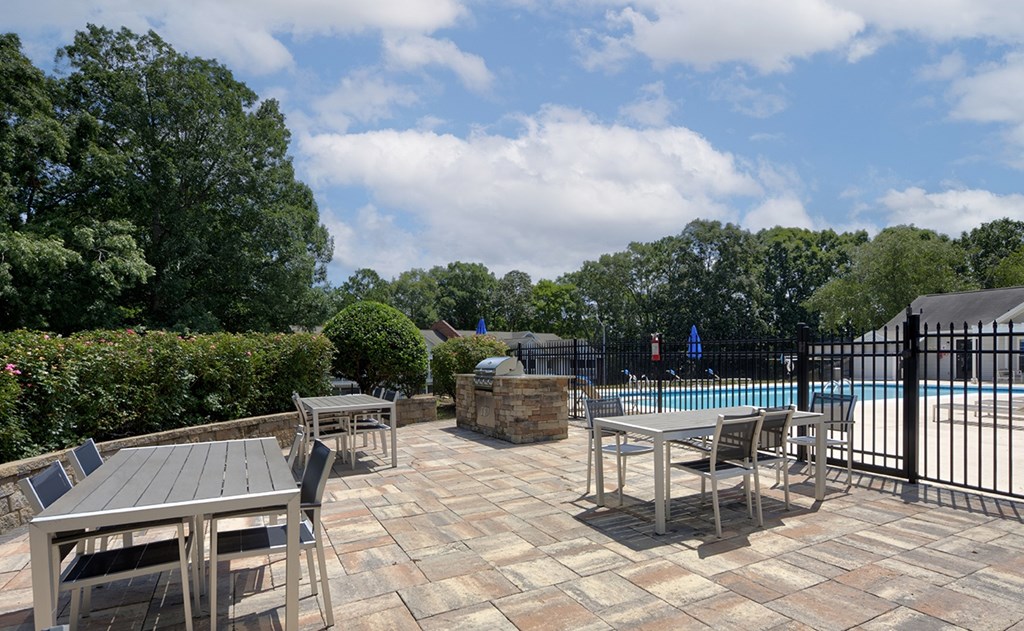 A pool surrounded by a black fence and a table with chairs.
