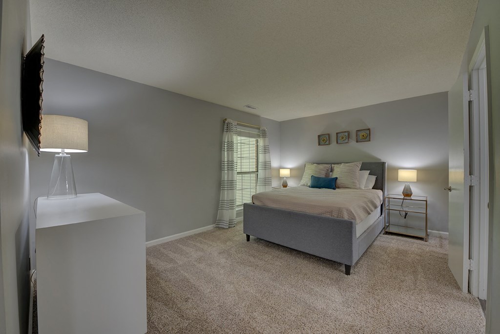 A bedroom with a bed, nightstand, and lamp.