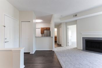 an empty living room with a fireplace and a kitchen