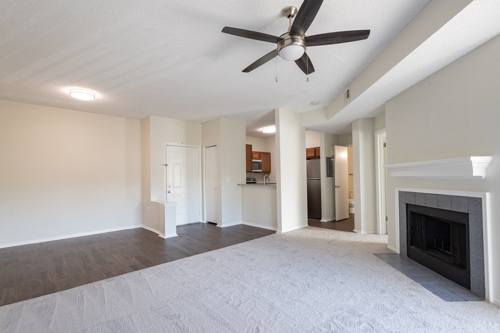 an empty living room with a fireplace and a ceiling fan