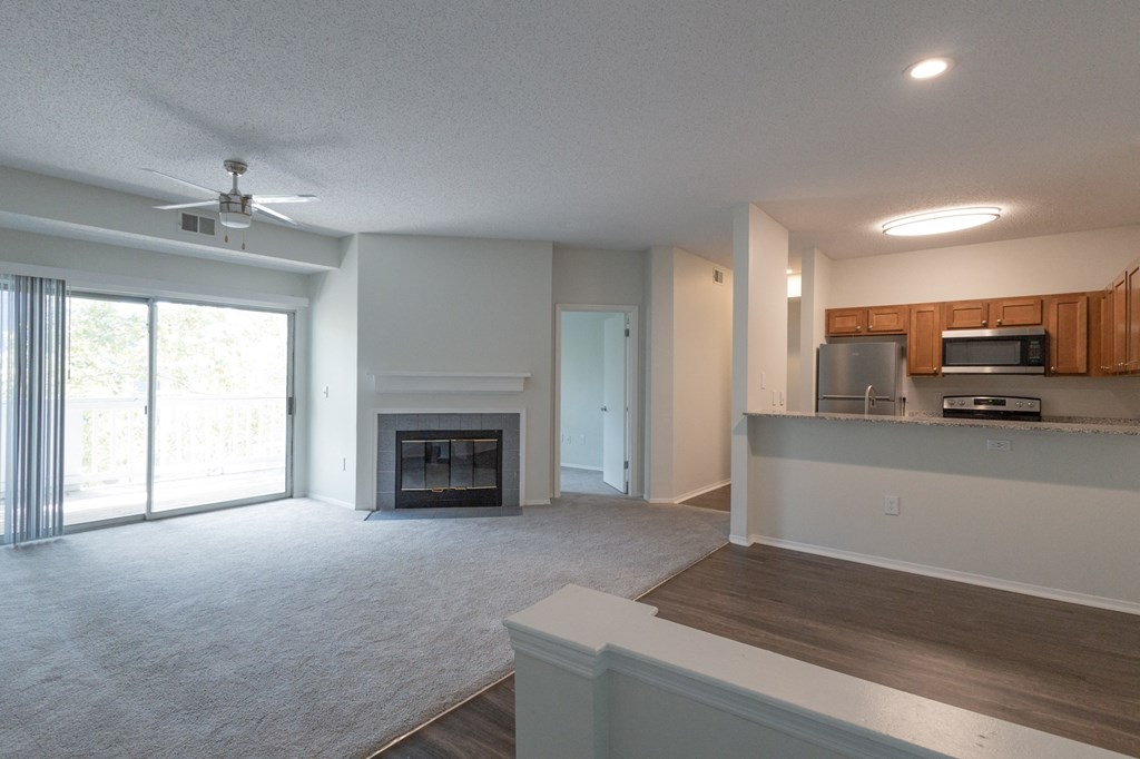 an empty living room with a fireplace and a kitchen