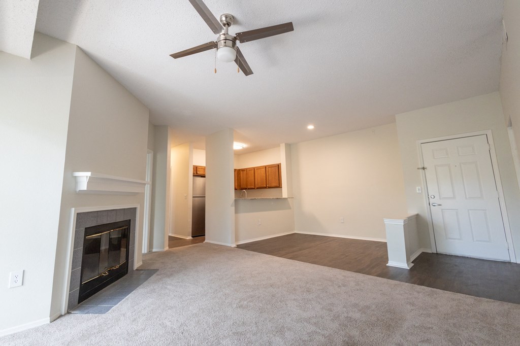 an empty living room with a fireplace and a ceiling fan
