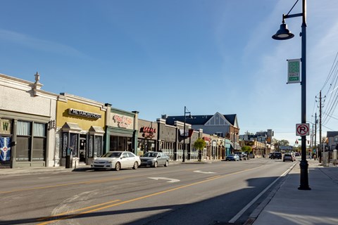 A street view with a no parking sign on a pole.