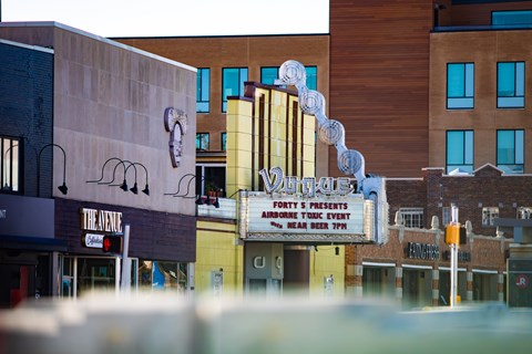 A blurry image of a street with a cinema advertising an event.