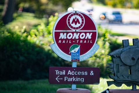 A sign for the Monon Rail Trail is shown with a direction to trail access and parking.
