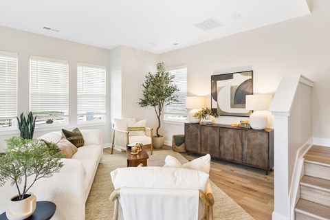 A living room with a white couch, a wooden coffee table, and a large painting on the wall.