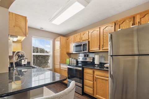 A kitchen with wooden cabinets and a stainless steel refrigerator.