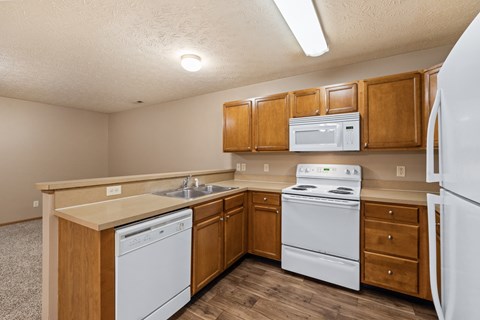 A kitchen with white appliances and wooden cabinets.