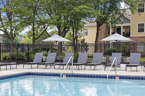 Shaded poolside seating area with loungers and umbrellas at Center Point Apartments offering a peaceful spot to relax outdoors.