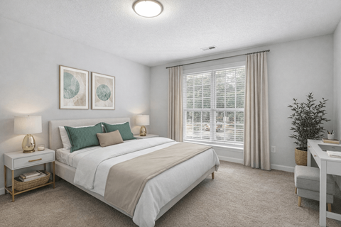 A bedroom with a large bed, a desk, and a window with blinds.