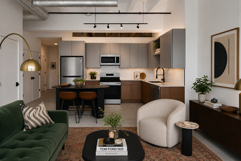 A modern living room with a green couch and a coffee table with a book titled "Tom Ford 002" on it.