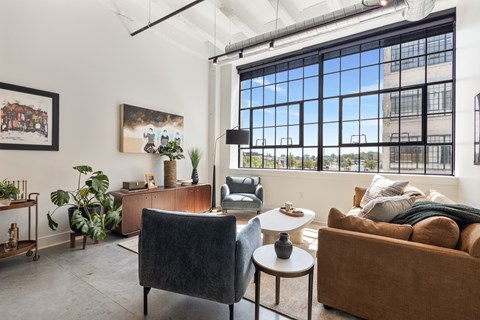 A living room with a brown couch, a black chair, and a table with a vase on it.