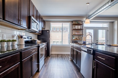 A modern kitchen with dark wood cabinets and stainless steel appliances.