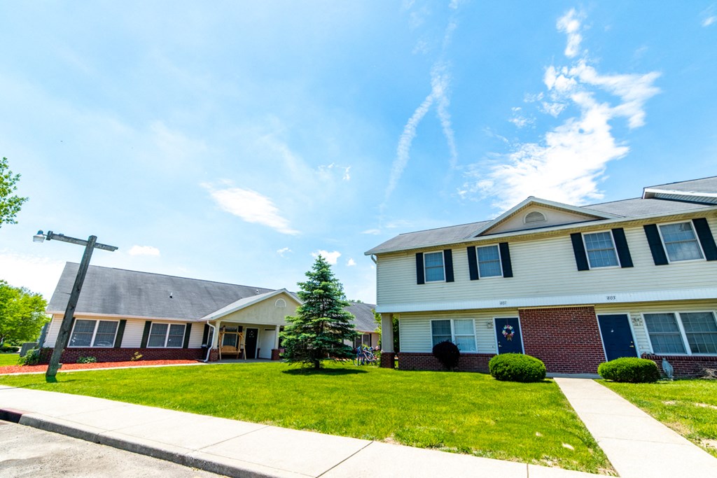 a house with a green lawn and blue sky in the background