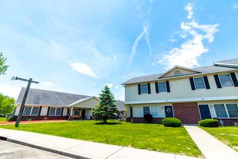 a house with a green lawn and blue sky in the background