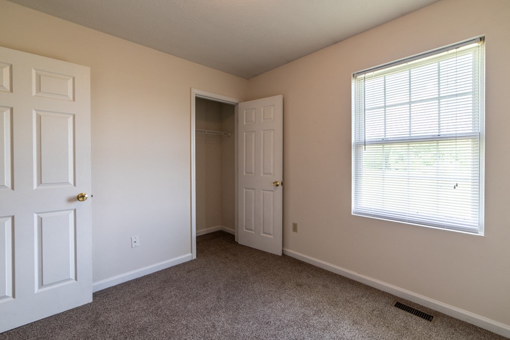 a bedroom with a large window and a closet