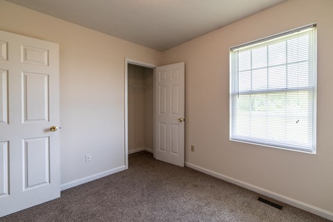 a bedroom with a large window and a closet