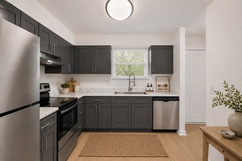 A modern kitchen with dark grey cabinets and stainless steel appliances.