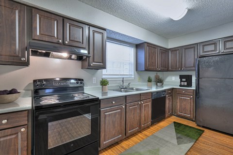 A kitchen with dark wood cabinets and a black stove top oven.