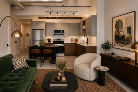 A modern kitchen with a green couch and a coffee table in the foreground.
