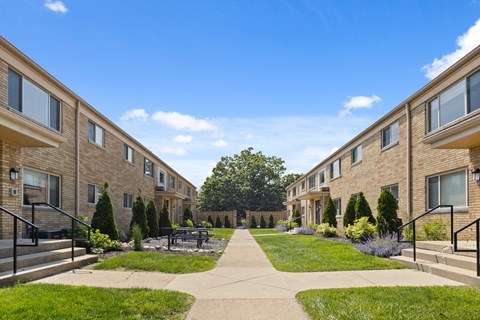 Beautifully landscaped courtyard at Monon Court Apartments in Broad Ripple, IN, with beige brick buildings and community green space close to Monon Trail access.
