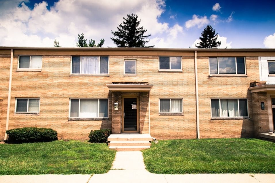 a brick apartment building with grass in front of it
