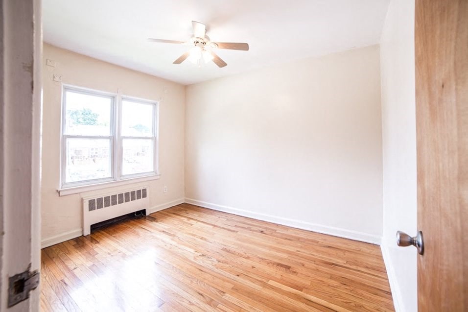 an empty room with wood floors and a ceiling fan