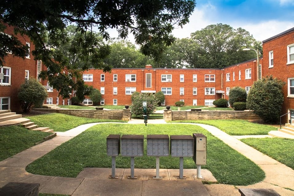 a bench in the middle of a lawn in front of a brick building