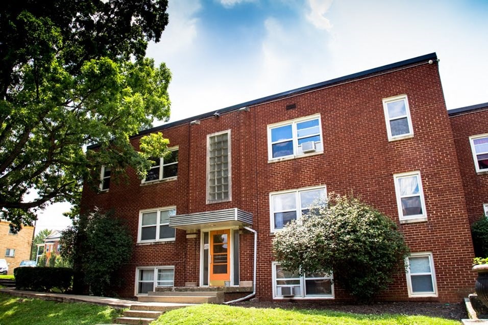 a red brick house with a tree in front of it